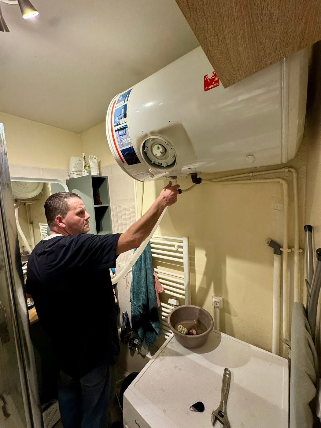 Plombier des Ets TORTOSA raccordant un chauffe-eau