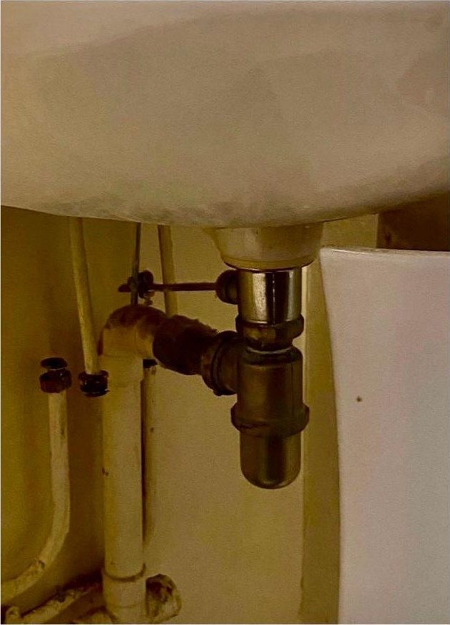Ancien siphon métal sous un lavabo